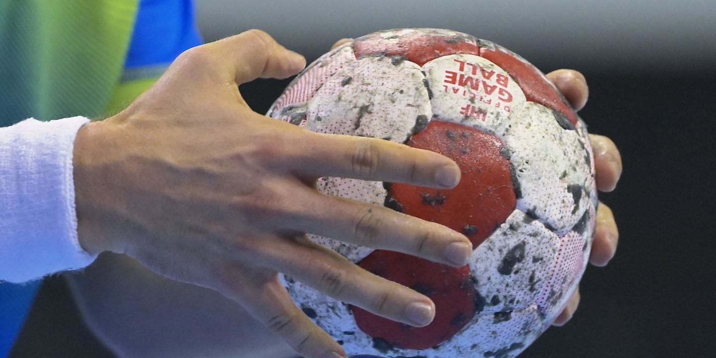 Ein Handballspieler hält den Spielball in den Händen.